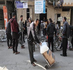 مواطنون يحصلون على الدقيق المقدمة من برنامج الغذاء العالمي في مركز توزيع المساعدات بمخيم البريج وسط قطاع غزة